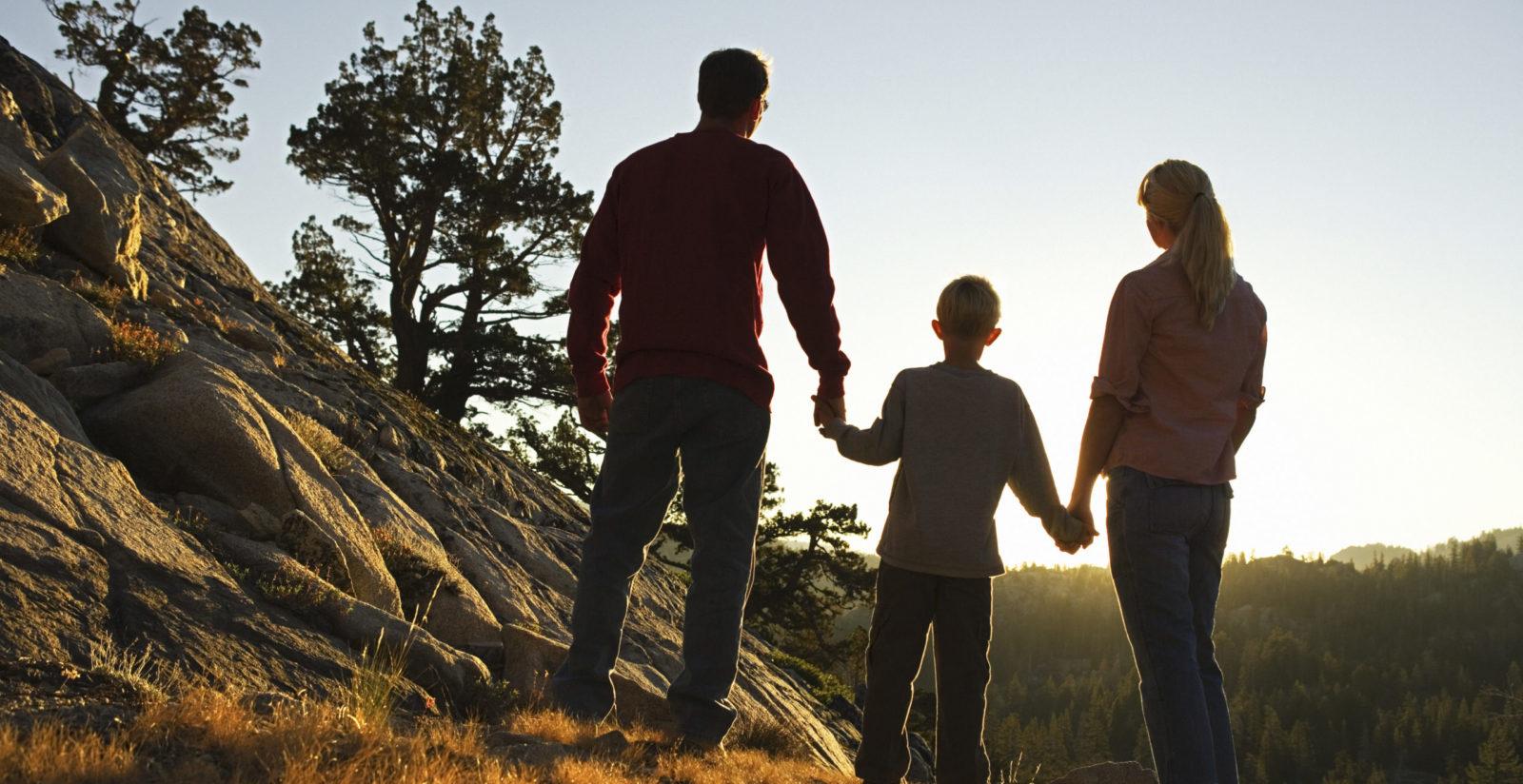 Family holding hands outdoors admiring sunrise